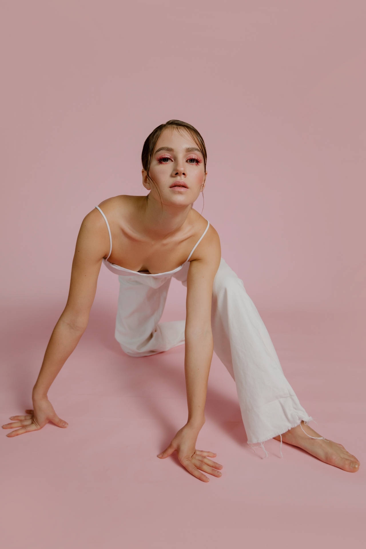 Woman in White Spaghetti Strap Dress Sitting on Pink Floor